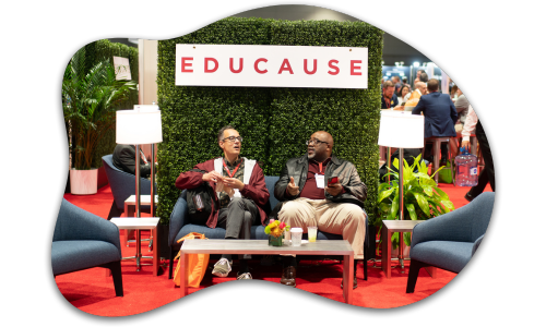 2 attendees sitting underneath and EDUCAUSE sign