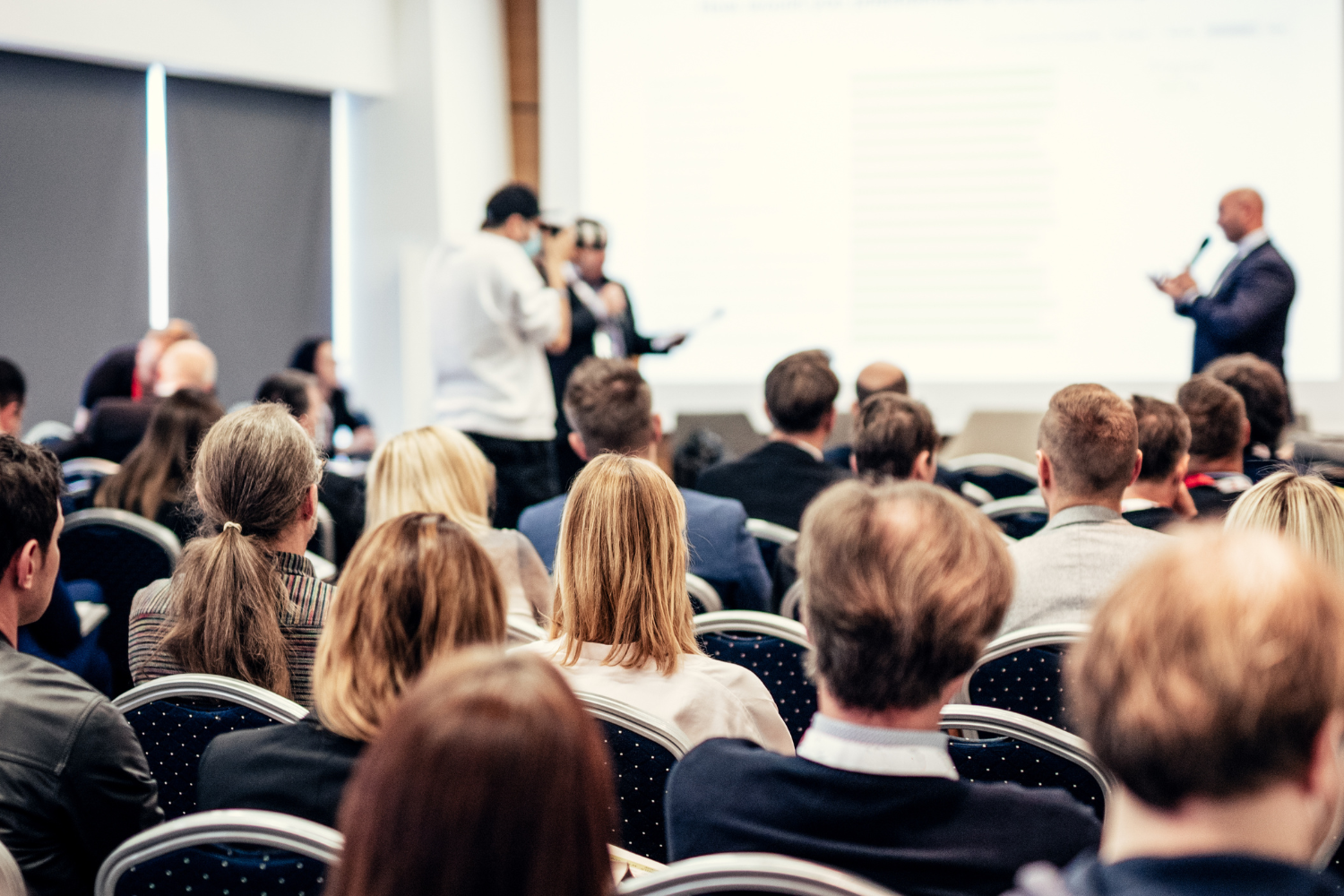 Several presenters in front of a room full of people